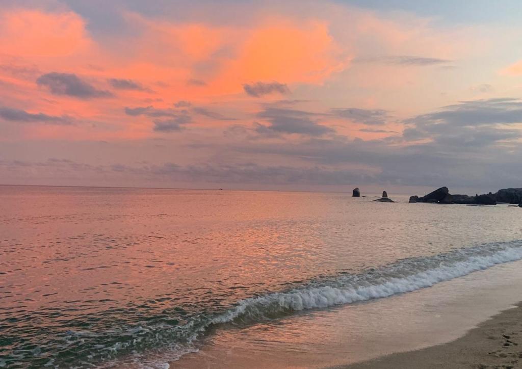 a sunset over the ocean with a sandy beach at 4U Resort Samui in Lamai