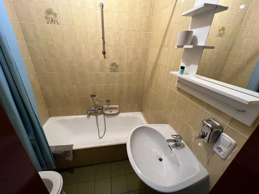 a bathroom with a sink and a tub and a toilet at F Hotel in Hörsching