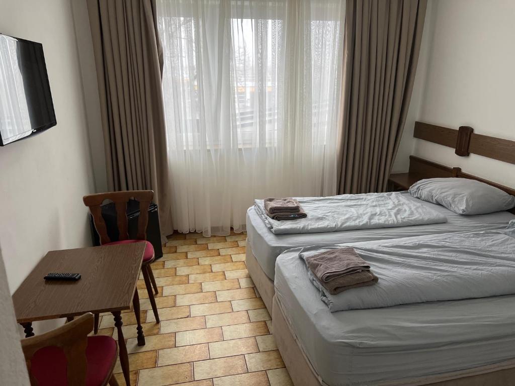 a hotel room with two beds and a table and a window at F Hotel in Hörsching