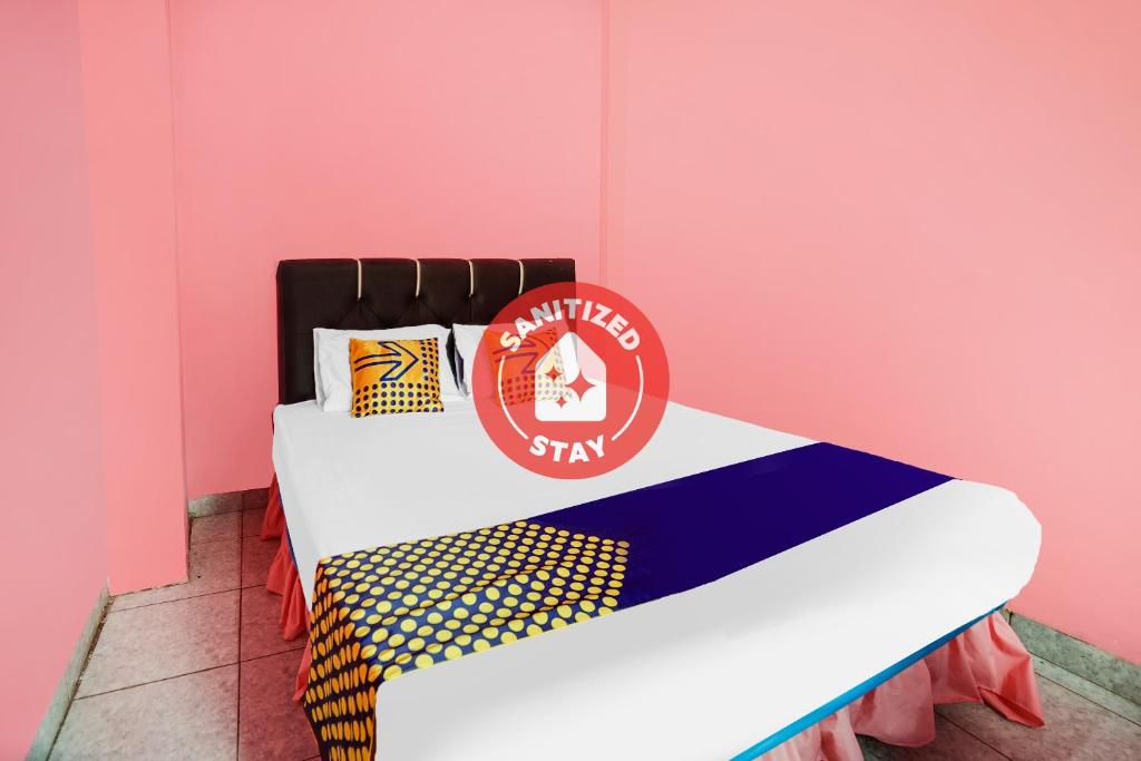 Bett in einem Zimmer mit einer rosa Wand in der Unterkunft OYO Life 92046 Garuda Residence in Palembang