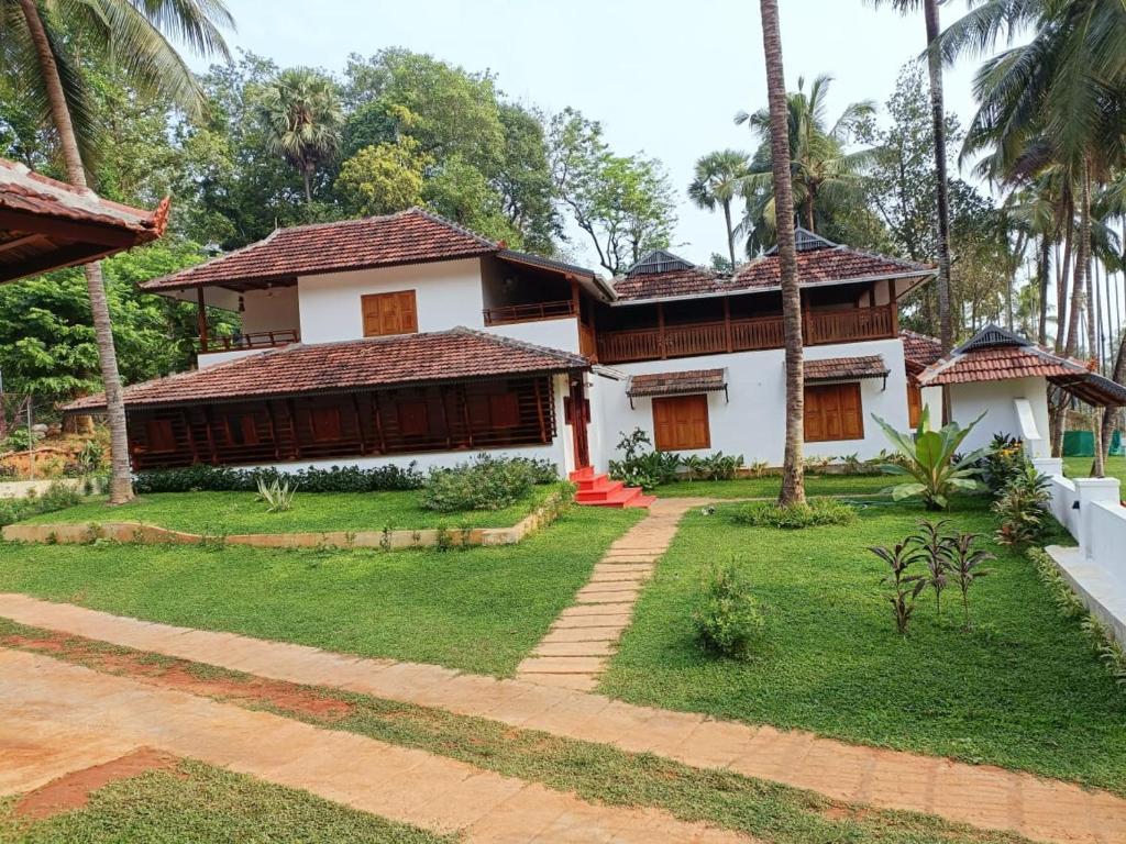 une maison avec un jardin en face dans l'établissement Kalappura Farm House Heritage, à Ottappālam