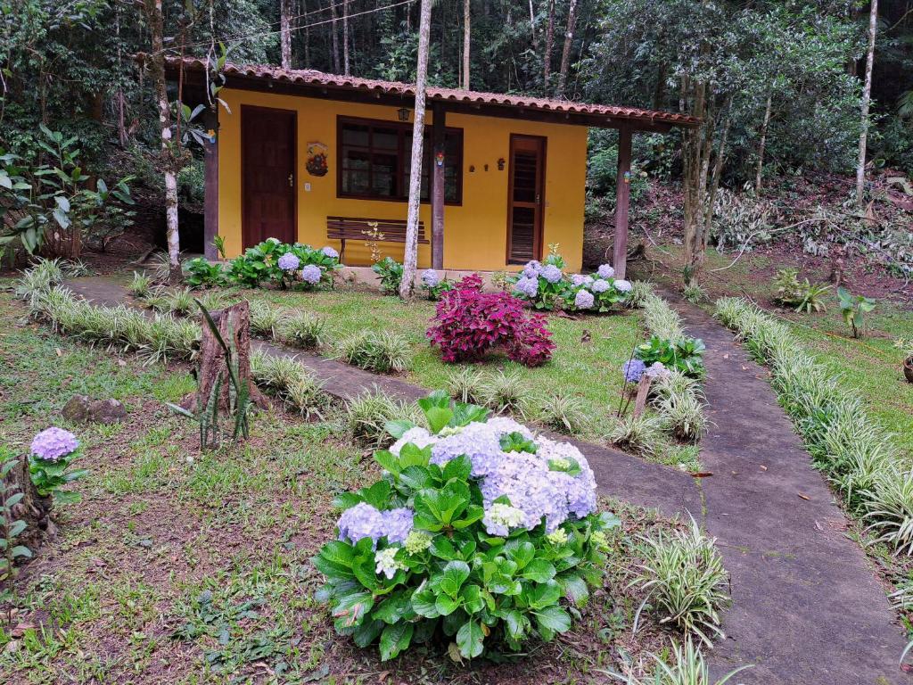 a small yellow house with flowers in front of it at Chalé Hakuna Matata in Lumiar