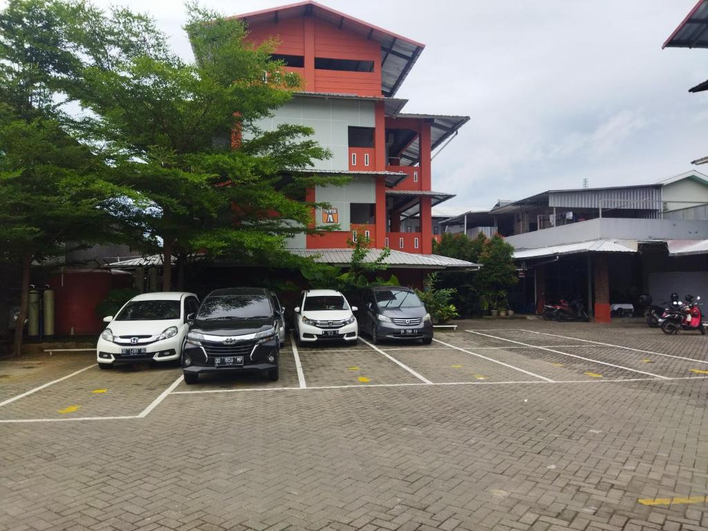 três carros estacionados num parque de estacionamento em frente a um edifício em OYO 92098 Kost Orange Syariah em Gusung