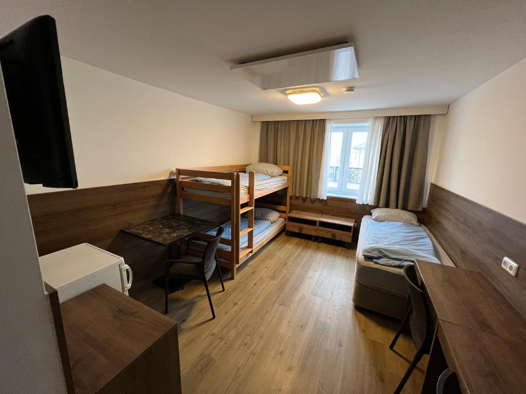 a room with two bunk beds and a desk with a television at F Hotel in Hörsching