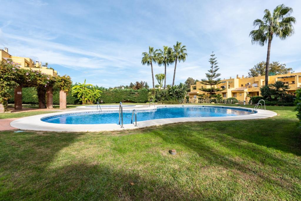 una piscina en un patio con palmeras en Apartamento Dúplex Los Cartujanos I, en Marbella