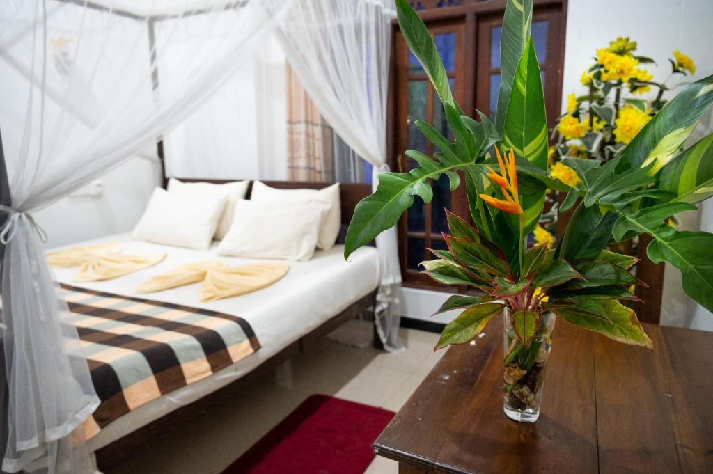 a bedroom with a bed and a table with flowers at Villa Sunimal in Unawatuna