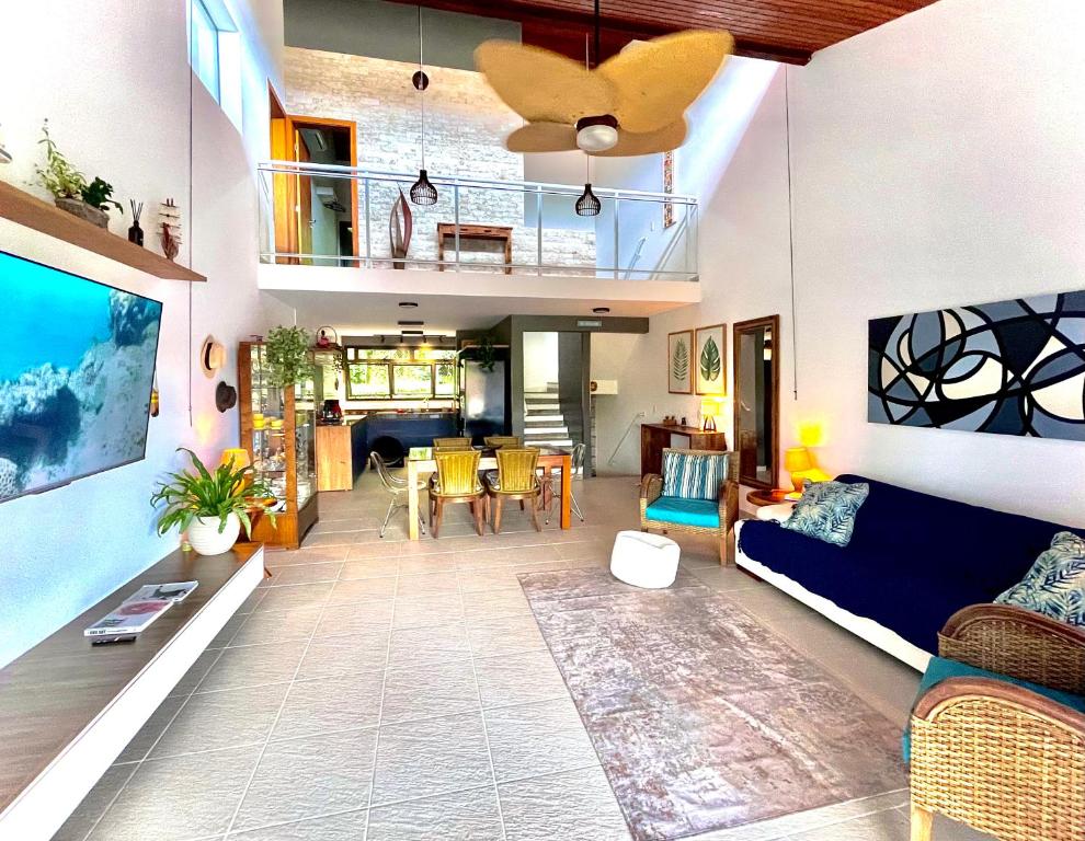 ein Wohnzimmer mit einem blauen Sofa und einem Esszimmer in der Unterkunft Delícia de casa em Barra do Una a 5 min de Juquehy! in São Sebastião