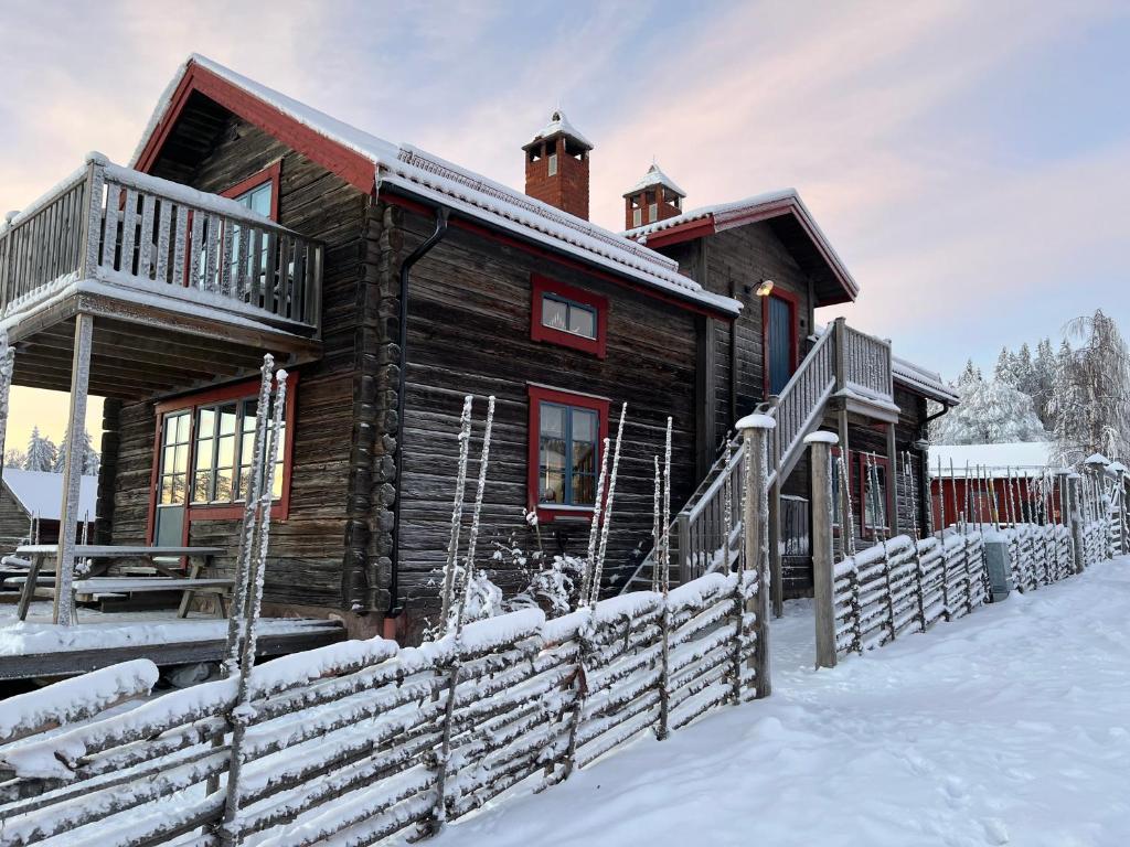 una cabaña de madera en la nieve con un patio cubierto de nieve en Brudtallen en Fryksås