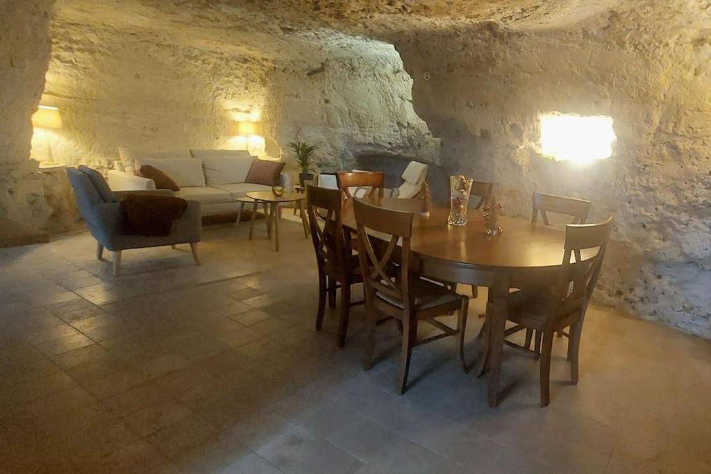 a dining room with a table and chairs and a couch at Troglo entre Caves et Châteaux in Montlouis-sur-Loire