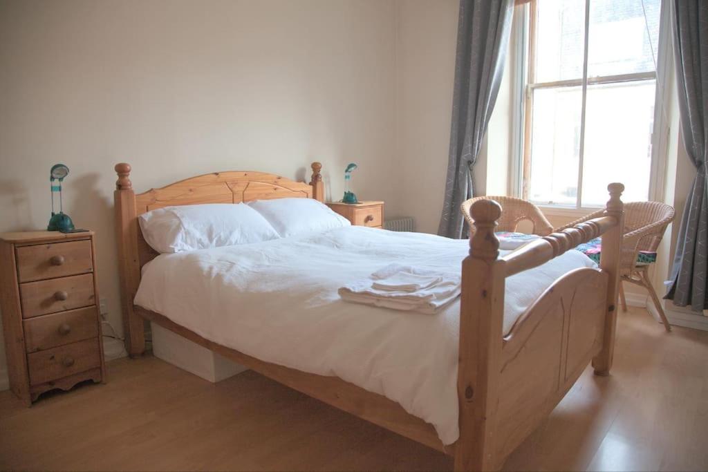 a bedroom with a wooden bed and a window at Cosy n Comfy Flat in Historic Heart of Edinburgh in Edinburgh