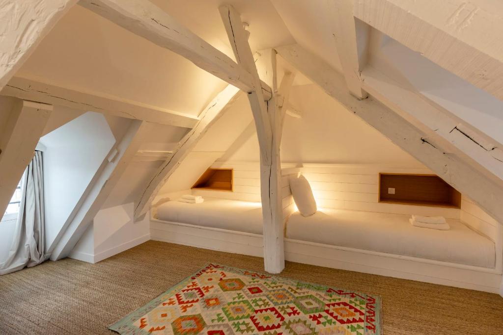 a attic room with two beds and a rug at La Demeure du Clocher 4 - On the Port and Place St Catherine - 8 P in Honfleur