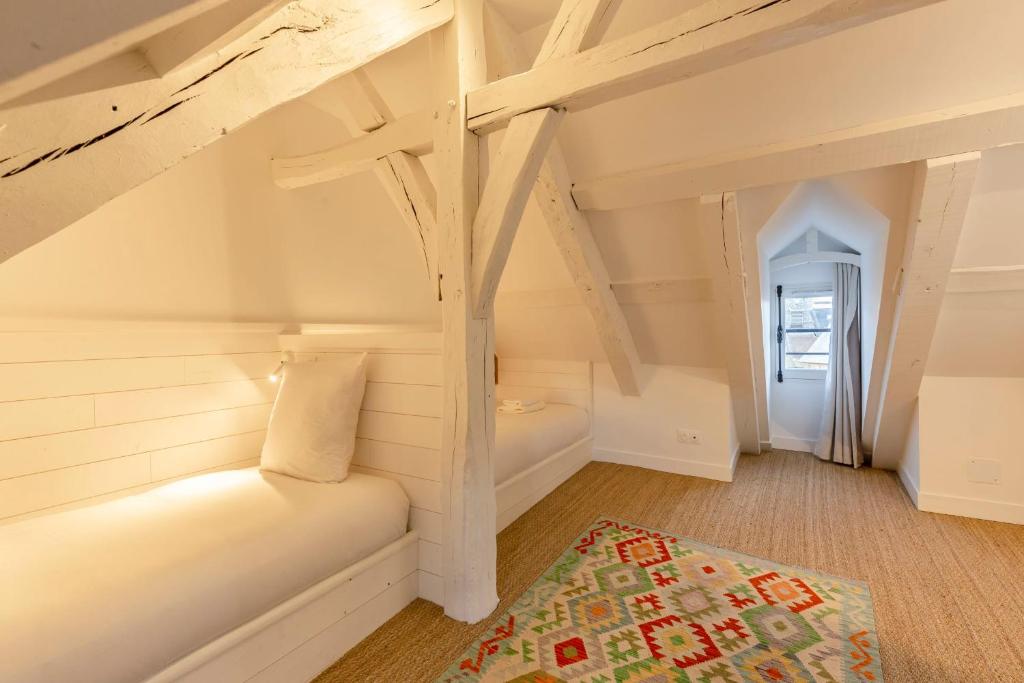 a attic room with a bed and a rug at La Demeure du Clocher 4 - On the Port and Place St Catherine - 8 P in Honfleur