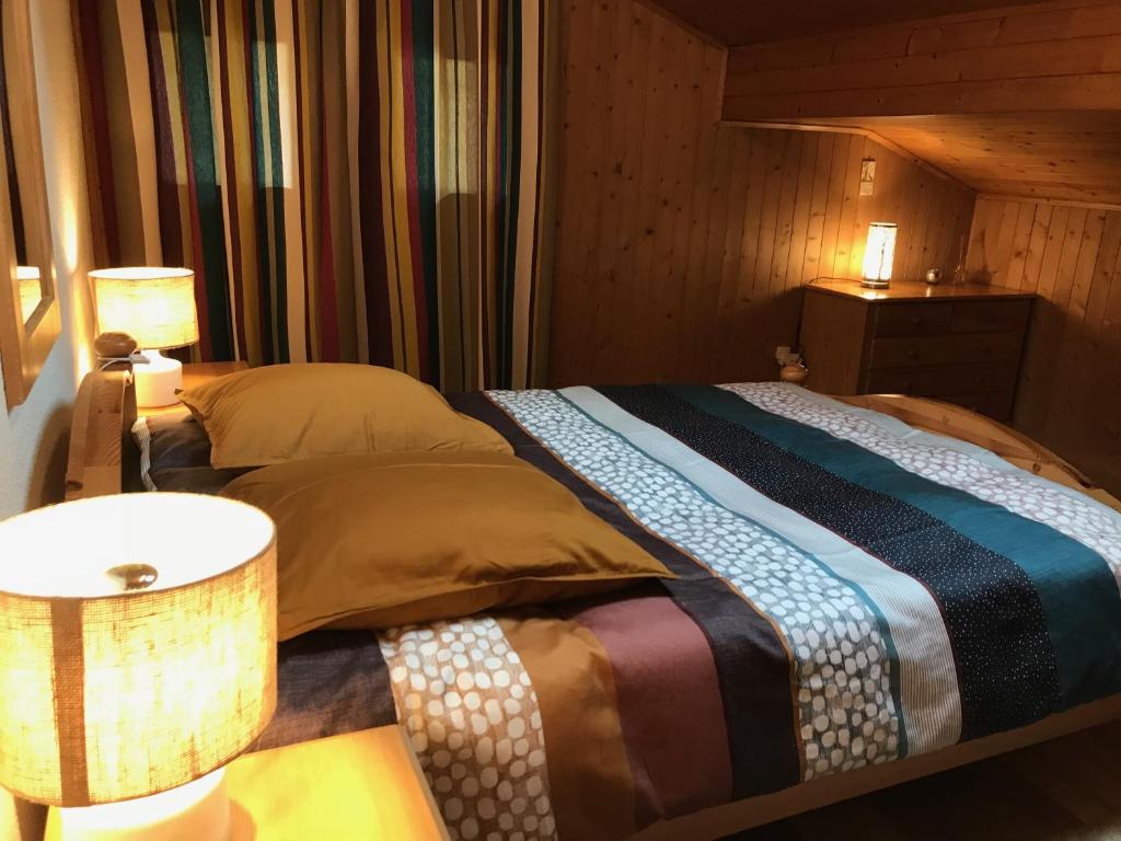 ein Schlafzimmer mit einem Bett, zwei Lampen und einem Tisch in der Unterkunft Becca Miedzo appartement in Le Châble