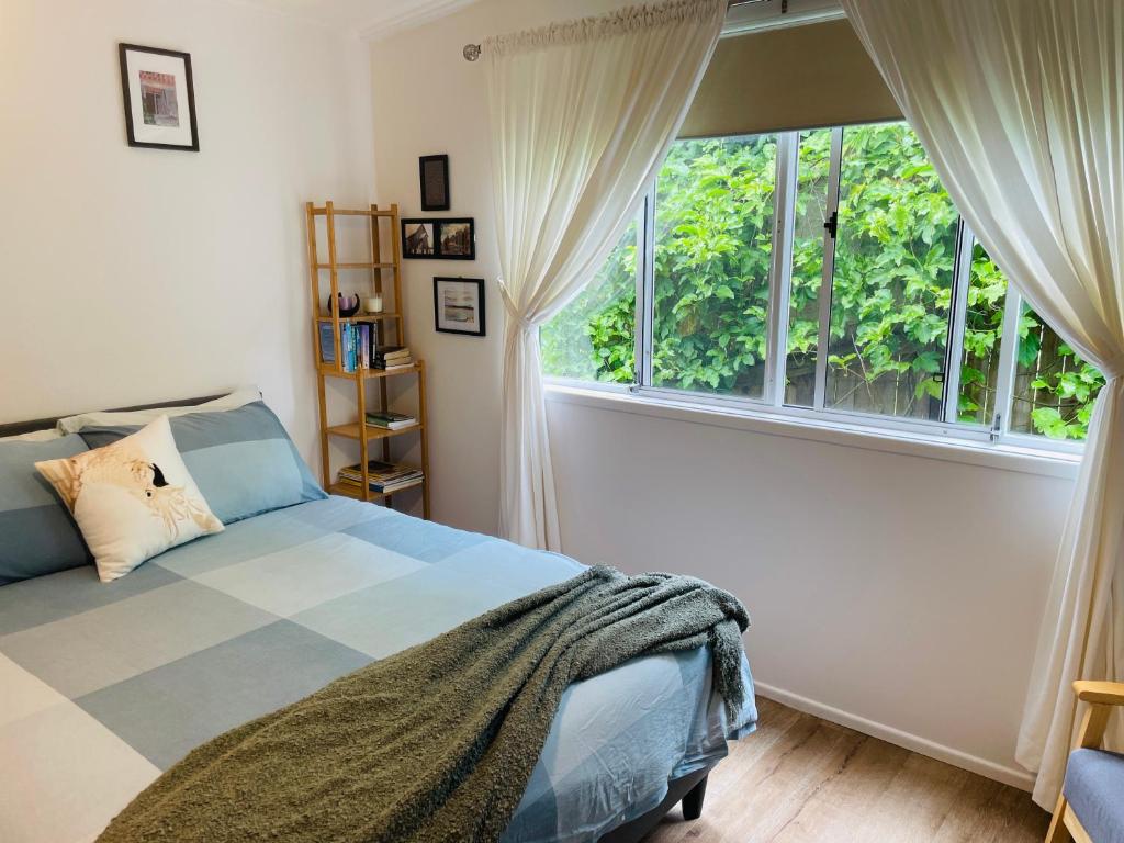 a bedroom with a bed and a large window at Eumundi Cottage in Town in Eumundi