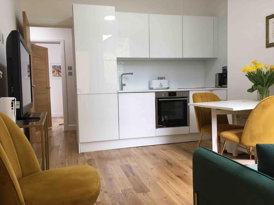 cocina con armarios blancos, mesa y sillas en Newly refurbished 2-bedroom flat in Notting Hill en Londres