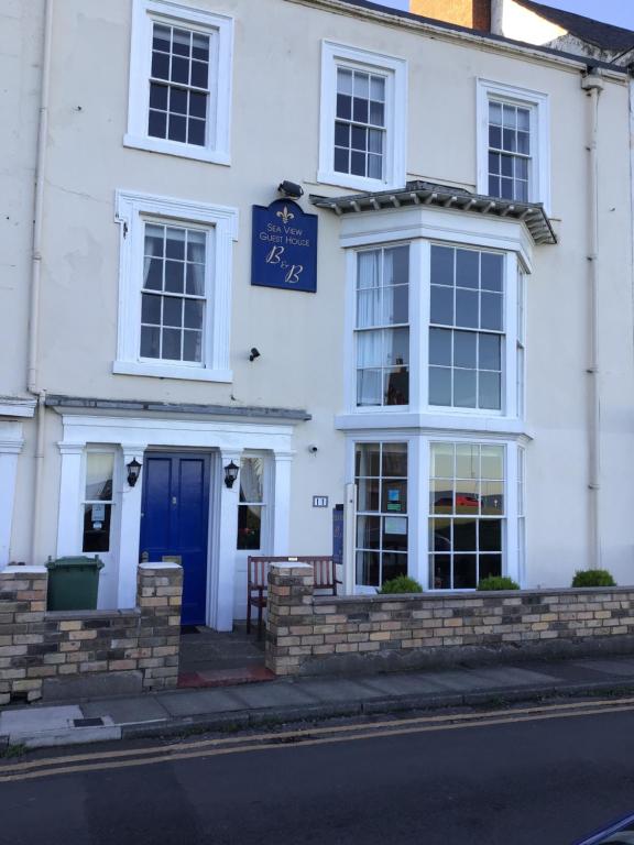 a white building with a blue door on a street at Sea View Guest House in Hartlepool