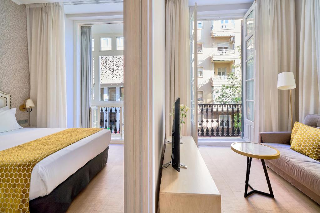 a hotel room with a bed and a couch and a window at Tandem Soho Suites in Málaga