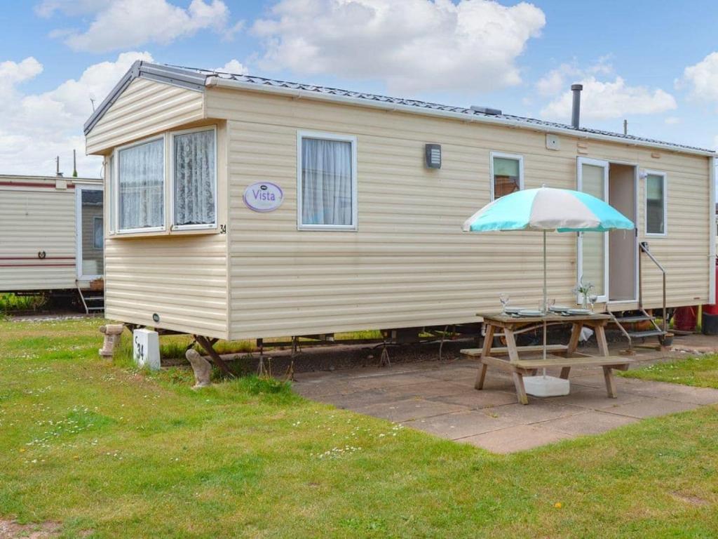a house with a picnic table and an umbrella at Norfolk Lavender Caravan - Sleeps 4 - WiFi and Sky TV Included in Bacton