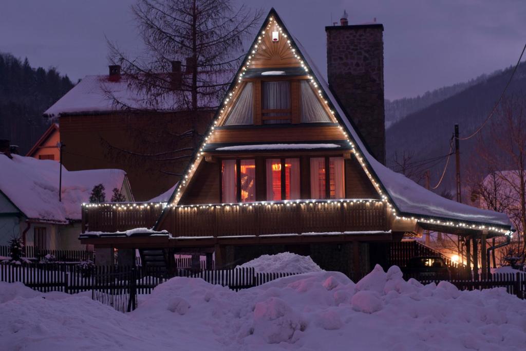 Una casa con luces en la nieve en Dom w Szczyrku - stylowy drewniany dom z kominkiem, en Szczyrk