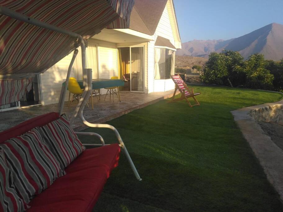 une véranda avec un canapé rouge sous un parasol dans l'établissement Casa Mamalluca, à Vicuña