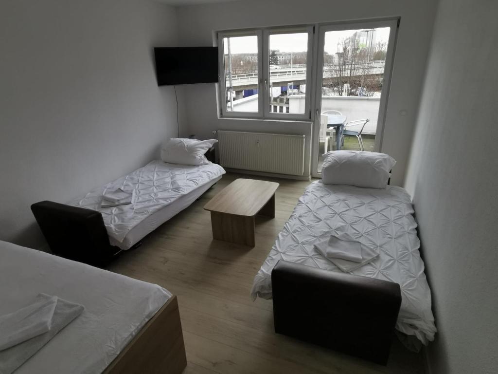 una camera con due letti e un tavolo e una finestra di Ferdimesse Apartments 2 a Colonia