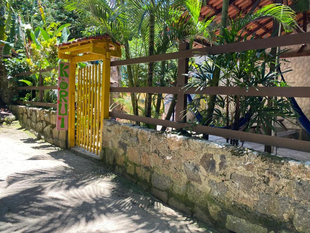 um portão amarelo numa parede de pedra ao lado de uma cerca em Pousada Korui em Abraão