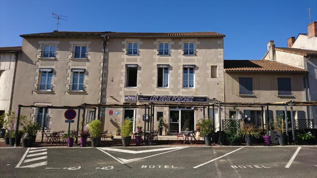 a building with a hotel in a parking lot at Hôtel Les Deux Porches in Verrières