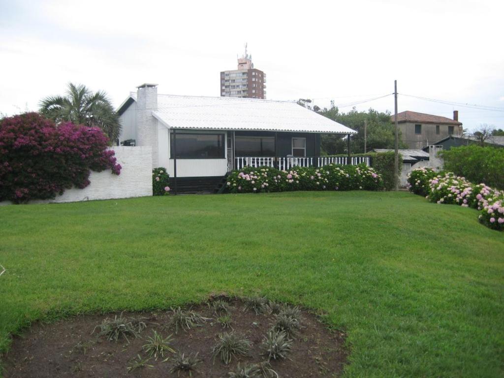 una casa blanca con un patio con césped verde en Chalet Chabot - frente al mar!, en La Paloma