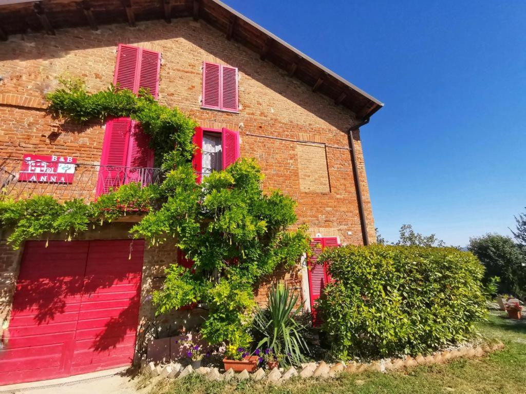 un edificio de ladrillo rojo con persianas rosas y plantas en A casa di Anna, en Vaglio Serra