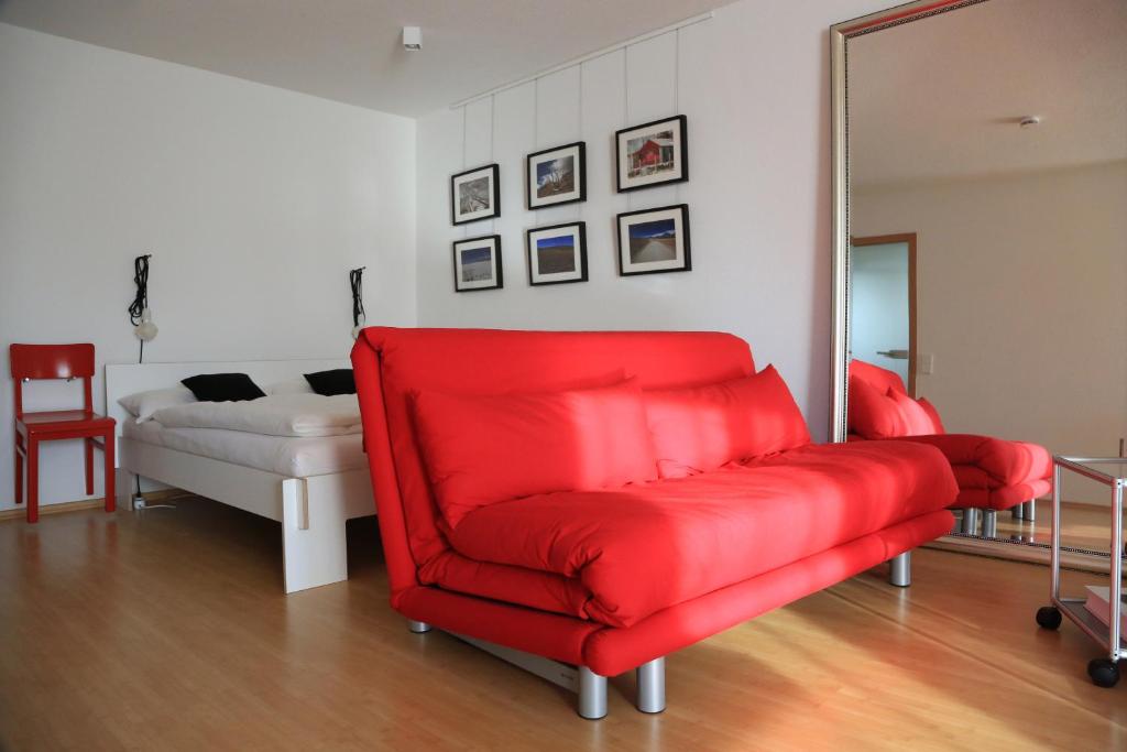 a red chair in a living room with a mirror at apartment-S Sonnenrain in Lörrach