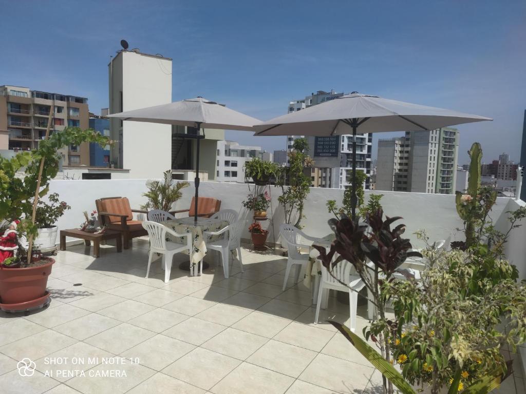 un patio con mesas, sillas y sombrillas en la azotea en Habitación RRB, en Lima