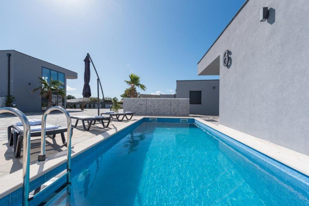 una piscina con 2 sillas y un edificio en More Exclusive Villas and Spa en Vir