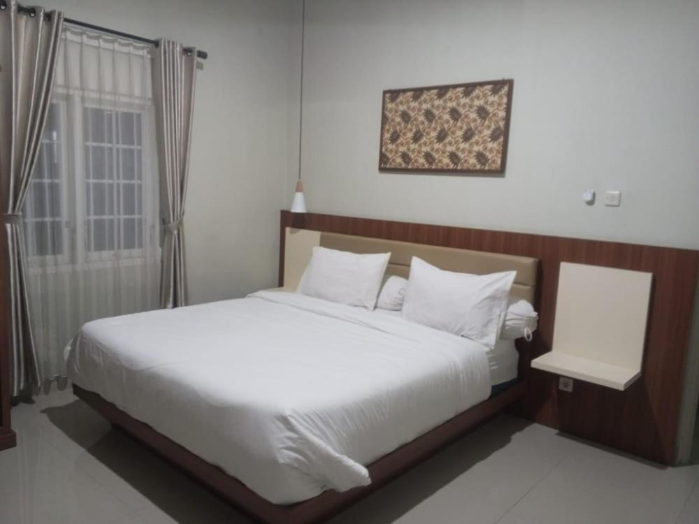 una camera da letto con un grande letto bianco e una finestra di Griya Sambilegi a Yogyakarta