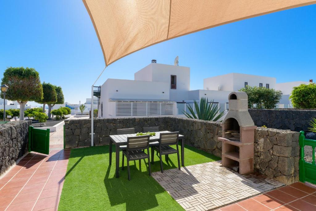 patio ze stołem i krzesłami oraz piecem do pizzy w obiekcie Casa Vela Marina, Puerto Calero w mieście Puerto Calero