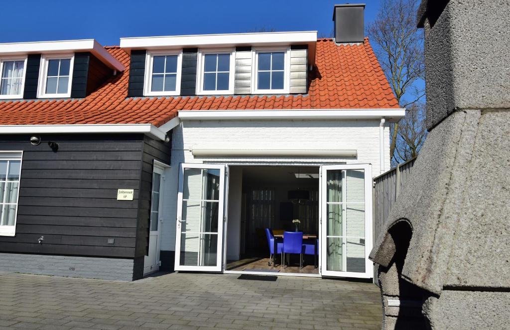 a house with an orange roof and blue chairs at Woning zeldenrust 6 in Oostkapelle