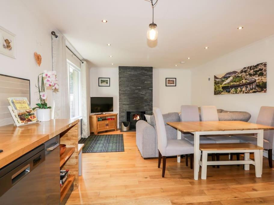 a kitchen and living room with a table and chairs at Stewart's Cottage, Aviemore Centre in Aviemore
