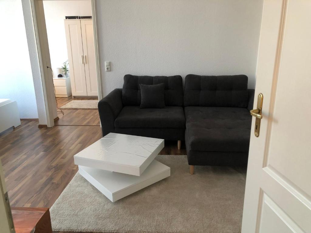 a living room with a black couch and a coffee table at APT im Herzen von Mainz in Mainz