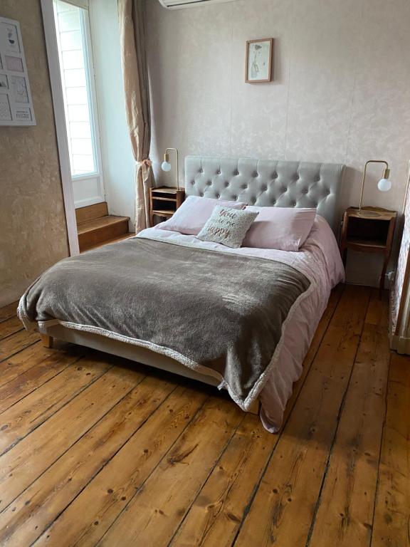 uma cama grande num quarto com piso em madeira em Suite privative dans maison de caractère em Le Faou