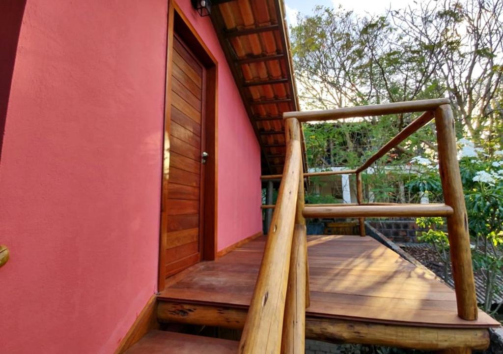 a wooden staircase leading to a house with a pink wall at Pacha - Bangalôs em Pipa in Pipa