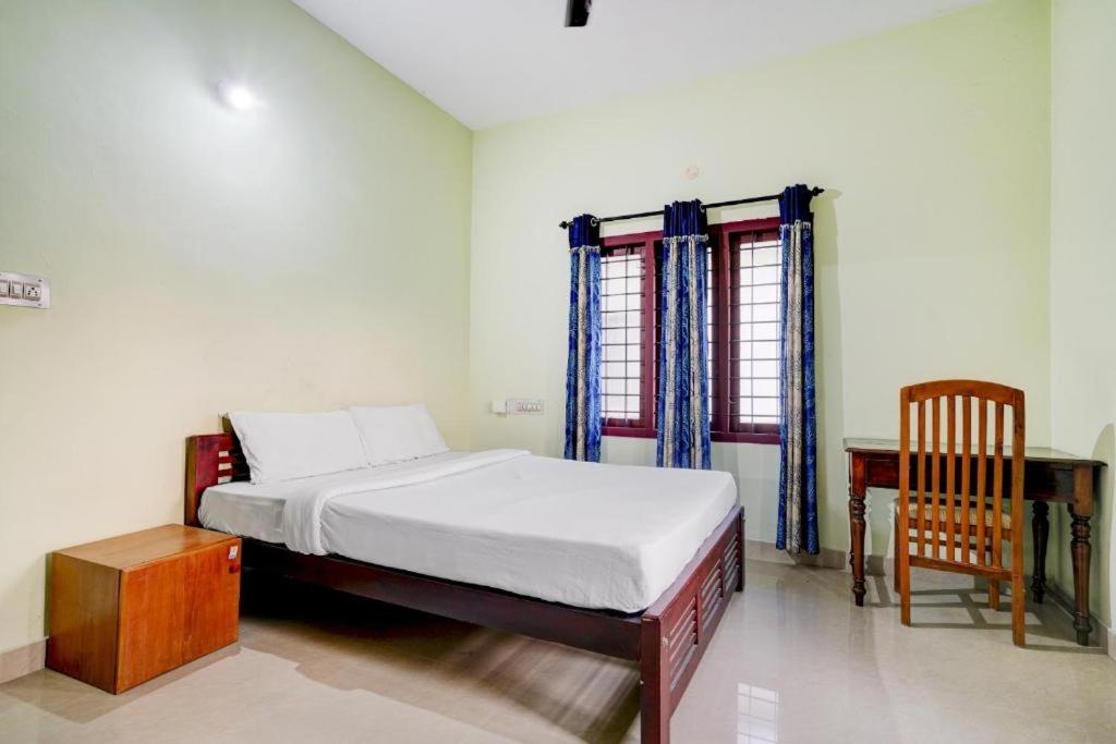 a bedroom with a bed and a desk and a window at Shalom Palace in Cochin