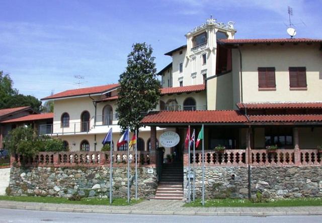 un grand bâtiment avec drapeaux devant lui dans l'établissement Hotel Ristorante Taverna Verde, à Piverone