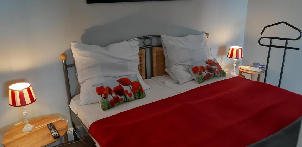 1 dormitorio con 1 cama con almohadas rojas y blancas en Ferienwohnung Silbermöwe, en Heiligenhafen