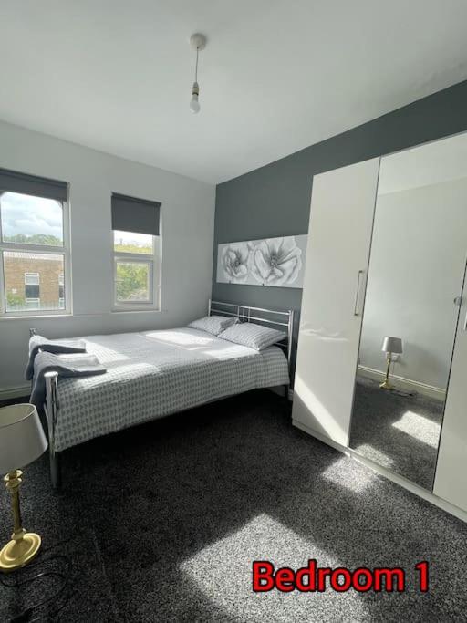 a bedroom with a bed and two windows at Cheerful 2 bedroom mid terrace house in BD2 in Bradford