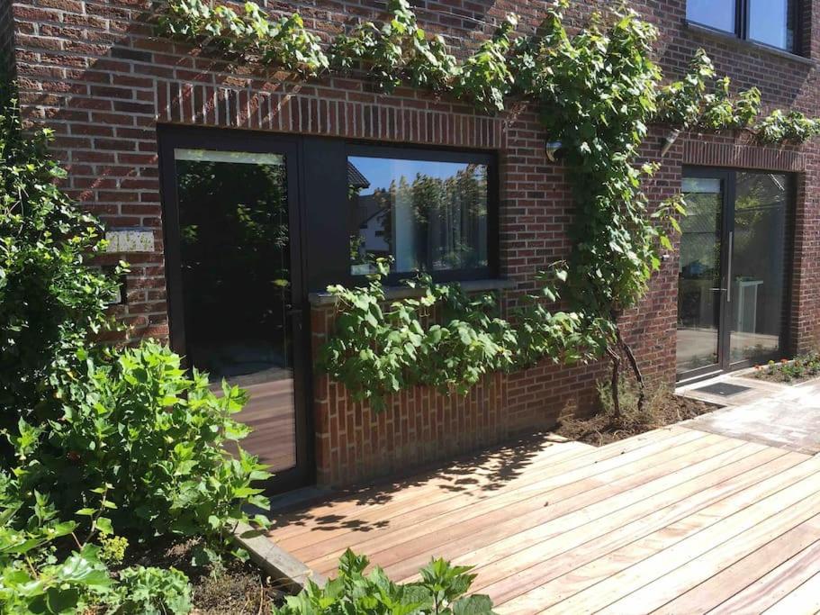 un edificio in mattoni con una porta e una terrazza in legno di 'het T-huisje' volledig ingerichte studio a Lovanio