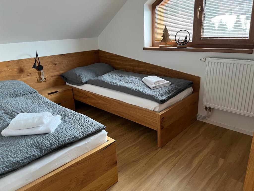 two beds in a room with wooden floors and a window at Mytho 2 in Mýto pod Ďumbierom