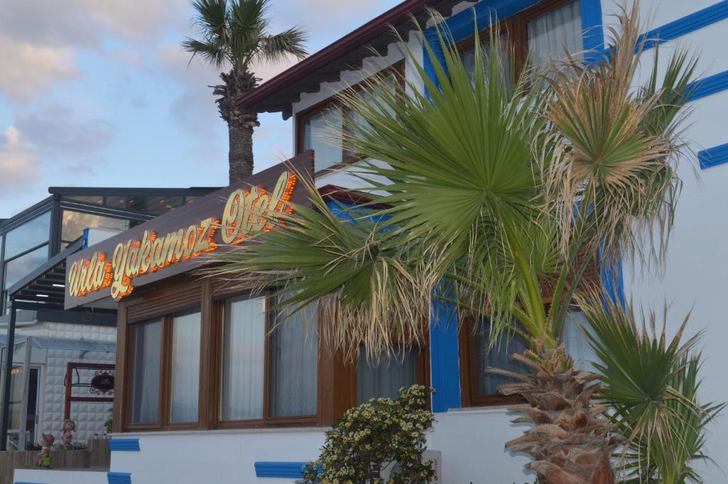 a hotel with a neon sign in front of a palm tree at Yakamoz Otel in Urla