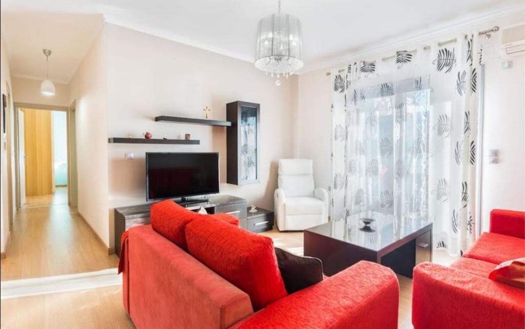uma sala de estar com duas cadeiras vermelhas e uma televisão em Eli Greko Apartament em Chania Town