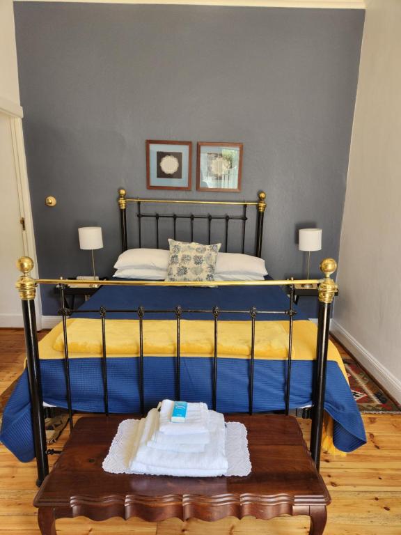 a bedroom with a bed with blue sheets and a table at Die Dorpshuis Graaff Reinet in Graaff-Reinet