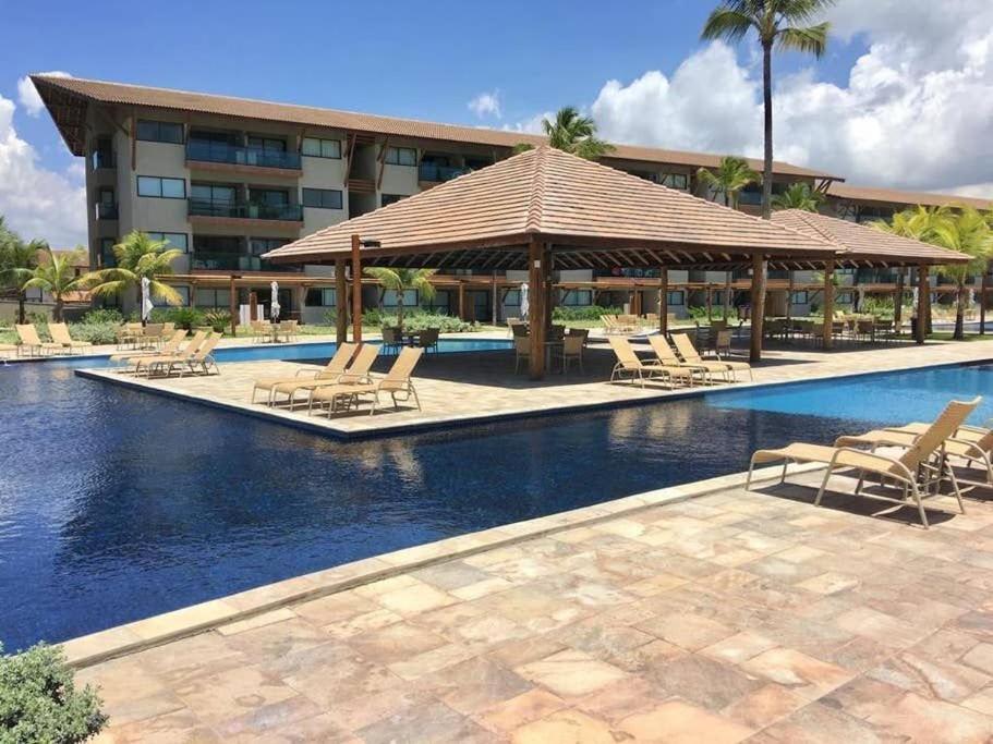 a swimming pool with lounge chairs and a hotel at Apt. 305 Bloco 7 · Flat com 2 quartos no La Fleur Polinésia - Muro Alto in Porto De Galinhas