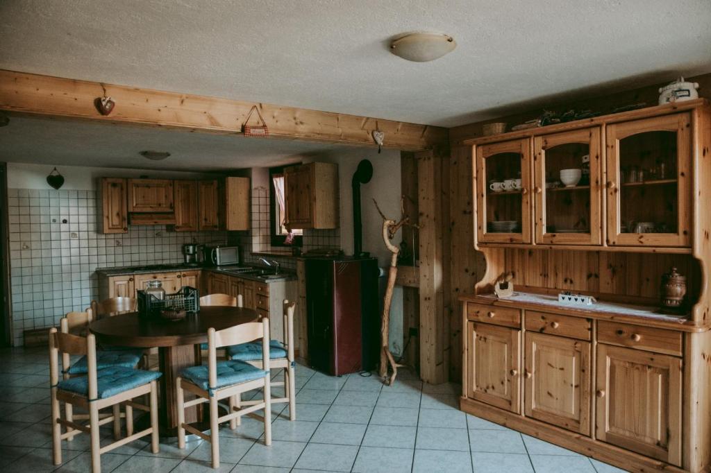 una cucina con armadi in legno, tavolo e frigorifero di La Tana della Lepre a Saint-Pierre
